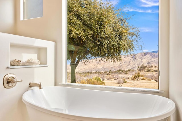 bathroom featuring a mountain view, plenty of natural light, and a bathing tub