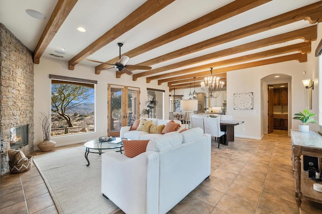 living room featuring a fireplace, ceiling fan with notable chandelier, and beamed ceiling