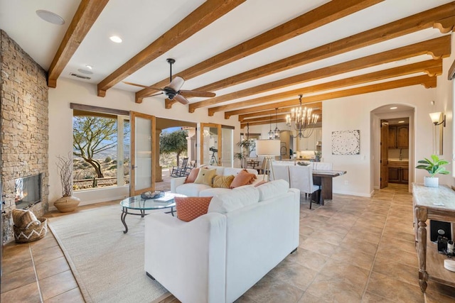 living room featuring ceiling fan with notable chandelier, a stone fireplace, and beamed ceiling