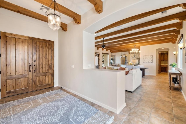 entryway with beamed ceiling and ceiling fan with notable chandelier