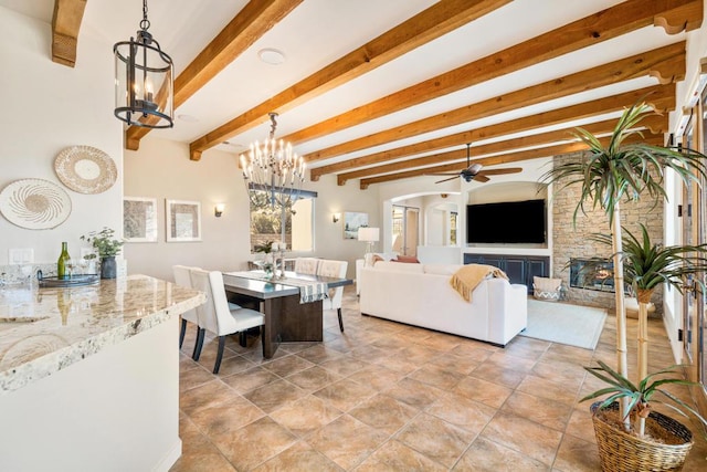 dining area with a fireplace, beam ceiling, and ceiling fan with notable chandelier