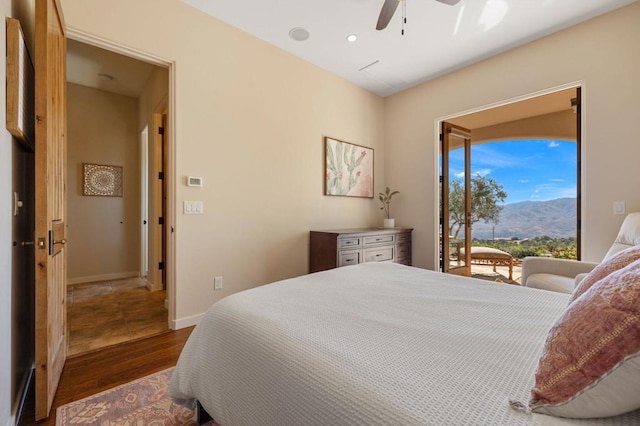 bedroom featuring ceiling fan, access to exterior, dark hardwood / wood-style floors, and a mountain view