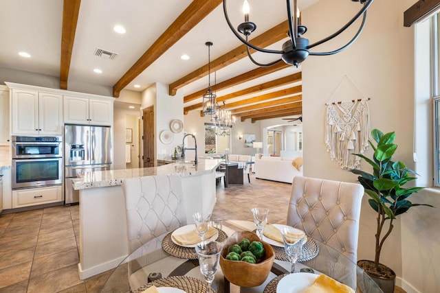 kitchen with ceiling fan with notable chandelier, white cabinets, beam ceiling, and appliances with stainless steel finishes