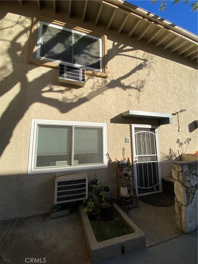 property entrance with heating unit, a patio area, and stucco siding