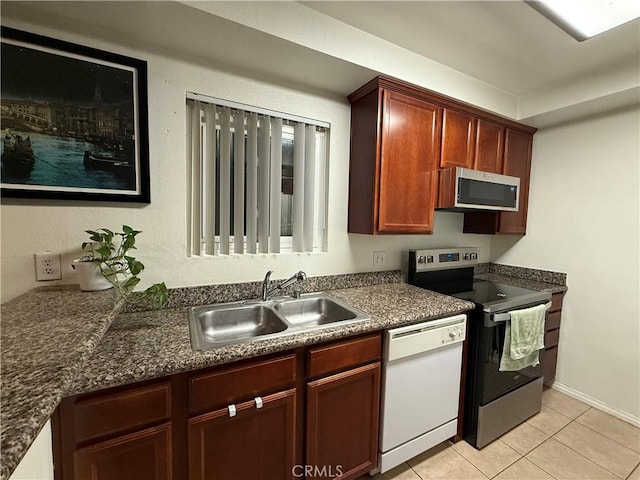 kitchen with appliances with stainless steel finishes, a sink, dark brown cabinets, and light tile patterned floors