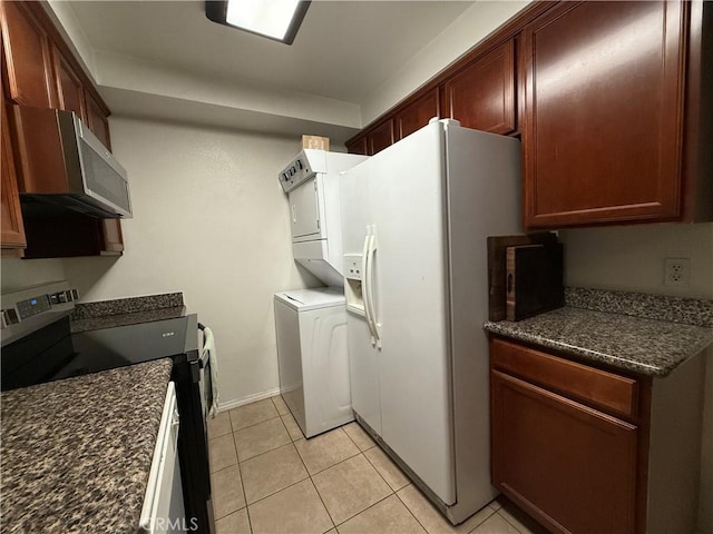 kitchen featuring stainless steel electric stove, stacked washer and clothes dryer, white fridge with ice dispenser, and light tile patterned floors