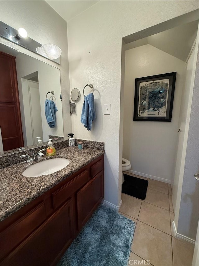 half bathroom featuring toilet, baseboards, vanity, and tile patterned floors