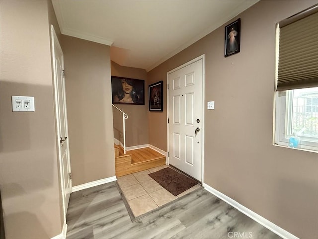 foyer entrance with stairway, light wood-style flooring, ornamental molding, and baseboards