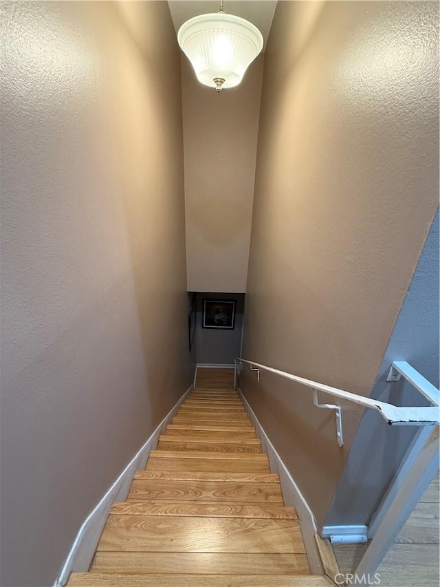 staircase with baseboards and wood finished floors