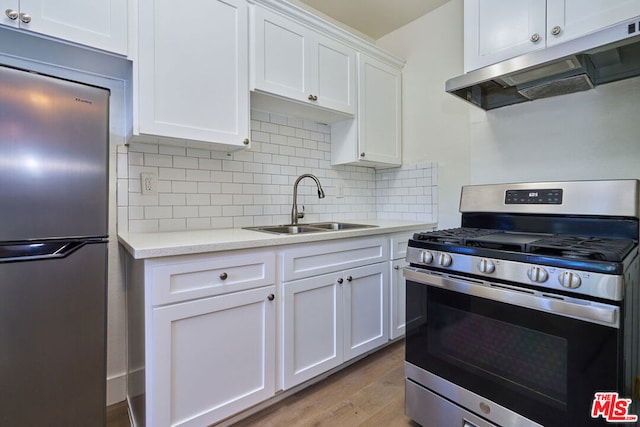 kitchen featuring white cabinetry, light hardwood / wood-style floors, appliances with stainless steel finishes, backsplash, and sink