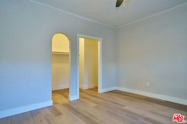 unfurnished bedroom with ceiling fan, a closet, a walk in closet, and light hardwood / wood-style flooring