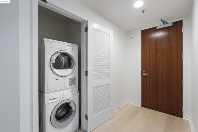 washroom featuring stacked washer / dryer and light hardwood / wood-style flooring