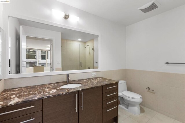 bathroom featuring walk in shower, vanity, tile walls, toilet, and tile patterned flooring