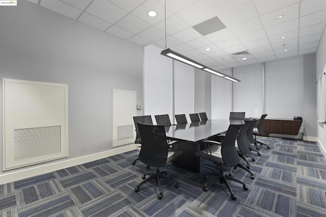 office space featuring dark colored carpet, a paneled ceiling, and a high ceiling