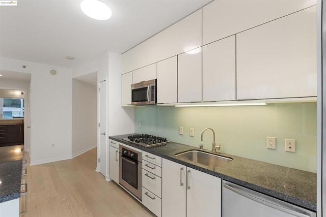 kitchen with white cabinets, sink, stainless steel appliances, and light hardwood / wood-style flooring