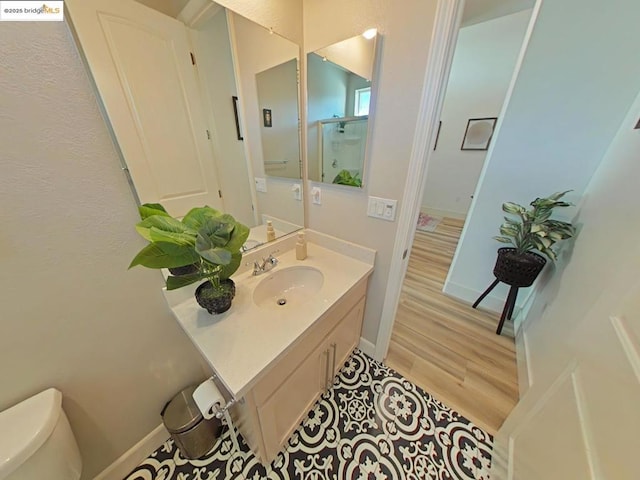 bathroom with a shower with shower door, hardwood / wood-style floors, toilet, and vanity