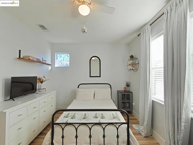 bedroom with ceiling fan, multiple windows, and light wood-type flooring