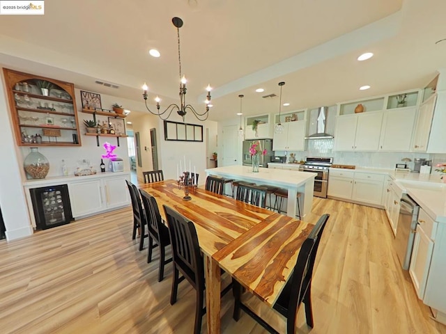 dining room with sink, light wood-type flooring, an inviting chandelier, and wine cooler