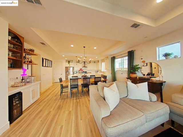 living room featuring light hardwood / wood-style floors, a tray ceiling, and a notable chandelier