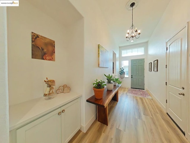 entrance foyer featuring light hardwood / wood-style floors, a towering ceiling, and a notable chandelier