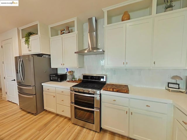 kitchen with wall chimney range hood, stainless steel appliances, and white cabinetry