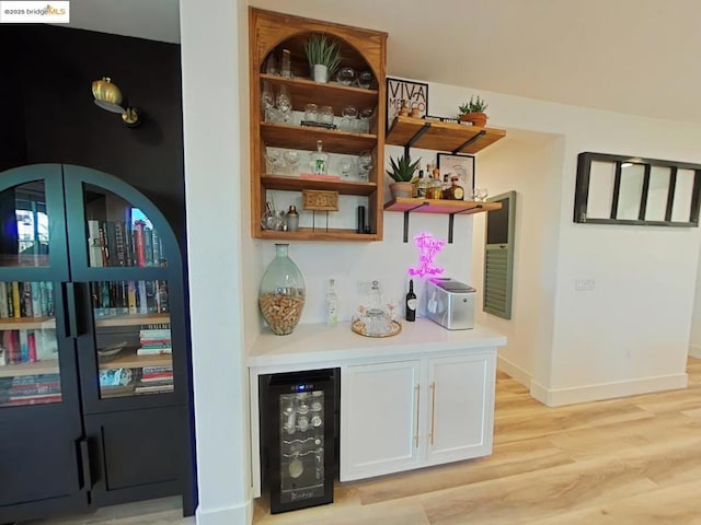 bar featuring white cabinetry, light hardwood / wood-style floors, and beverage cooler