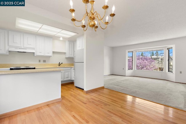 kitchen featuring a notable chandelier, white fridge, sink, white cabinetry, and hanging light fixtures