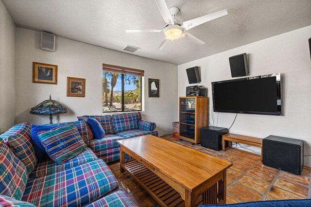 living room with a textured ceiling, ceiling fan, and tile patterned floors