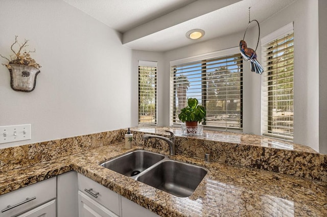 kitchen with sink, white cabinetry, and dark stone counters