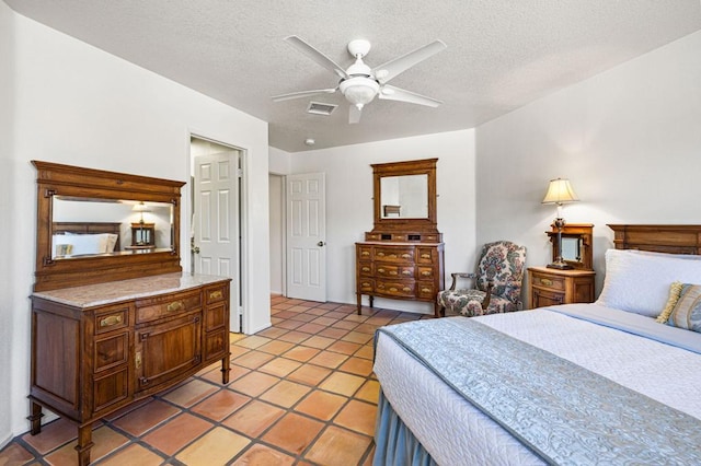 tiled bedroom with ceiling fan and a textured ceiling