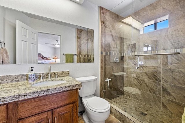 bathroom featuring ceiling fan, toilet, vanity, and a shower with door