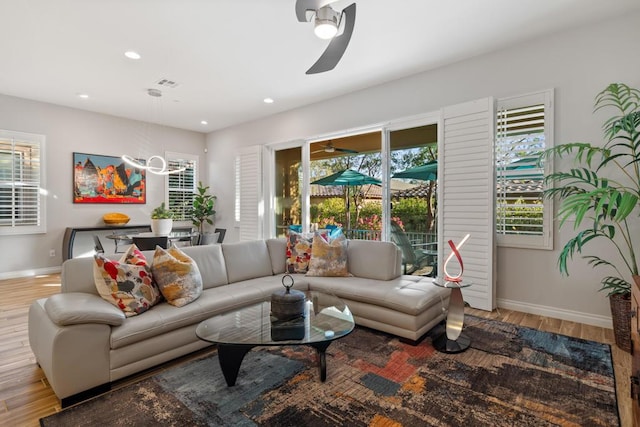 living room with ceiling fan with notable chandelier and hardwood / wood-style floors