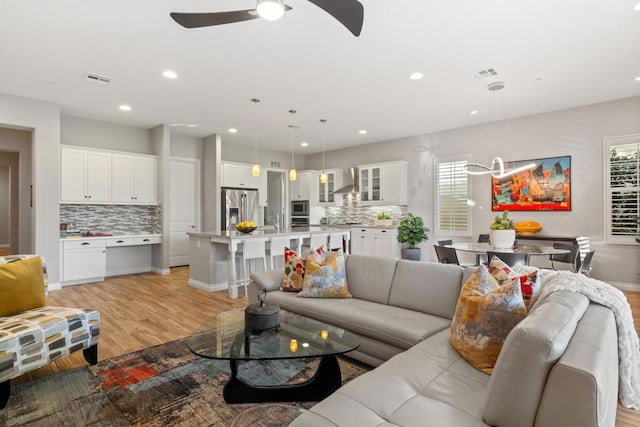 living room featuring ceiling fan, light hardwood / wood-style flooring, and sink