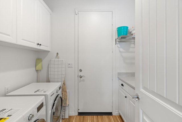 clothes washing area with light wood-type flooring, washing machine and clothes dryer, and cabinets