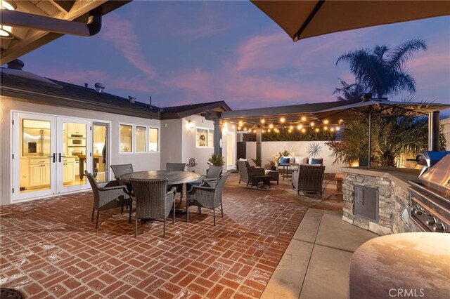 patio terrace at dusk with exterior kitchen and french doors