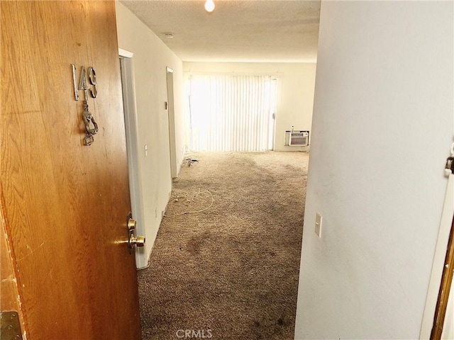 hall with a textured ceiling, a wall mounted AC, and carpet flooring