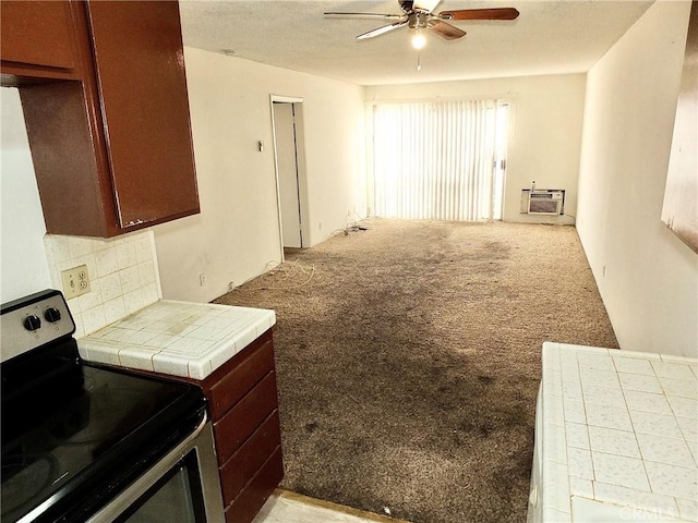 kitchen with an AC wall unit, tile counters, light carpet, electric stove, and ceiling fan