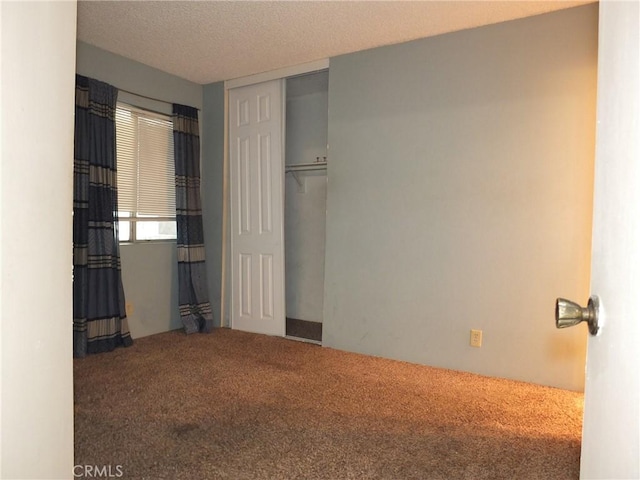 unfurnished bedroom with a textured ceiling, a closet, and carpet