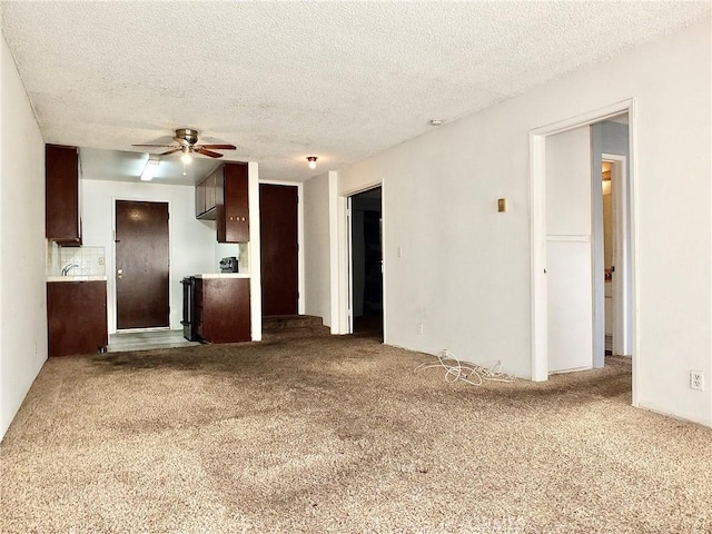 unfurnished living room featuring ceiling fan, a textured ceiling, and carpet flooring