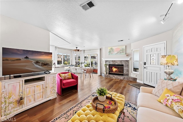 living room with a fireplace, dark hardwood / wood-style flooring, a textured ceiling, and track lighting