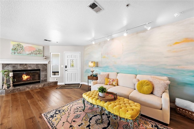 living room with wood-type flooring, a high end fireplace, and a textured ceiling