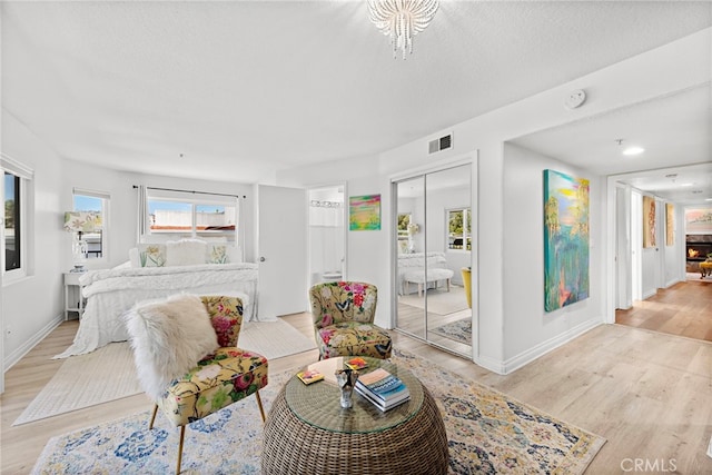 living room with light wood-type flooring, an inviting chandelier, and a textured ceiling