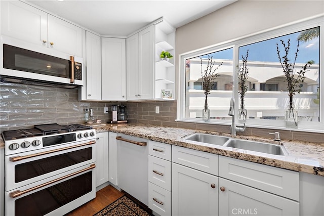 kitchen featuring double oven range, white cabinetry, light wood-type flooring, light stone counters, and sink