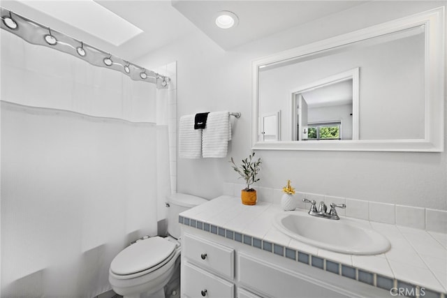 bathroom with toilet, vanity, and a skylight