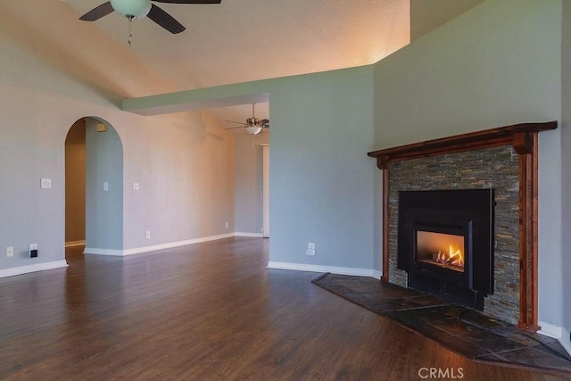 unfurnished living room featuring ceiling fan, dark wood-type flooring, a stone fireplace, and lofted ceiling