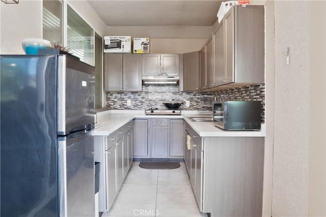 1714 Graybark Ave, Clovis, CA 93619 - kitchen featuring light countertops, freestanding refrigerator, backsplash, light tile patterned flooring, and under cabinet range hood