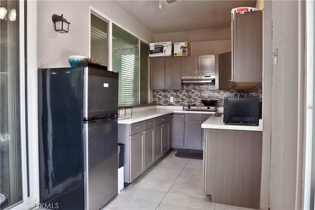 1714 Graybark Ave, Clovis, CA 93619 - kitchen with tasteful backsplash, light tile patterned floors, light countertops, freestanding refrigerator, and under cabinet range hood