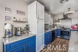 kitchen featuring sink, dark wood-type flooring, blue cabinetry, white cabinetry, and stainless steel range