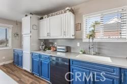 kitchen featuring blue cabinetry, sink, white cabinetry, plenty of natural light, and black dishwasher