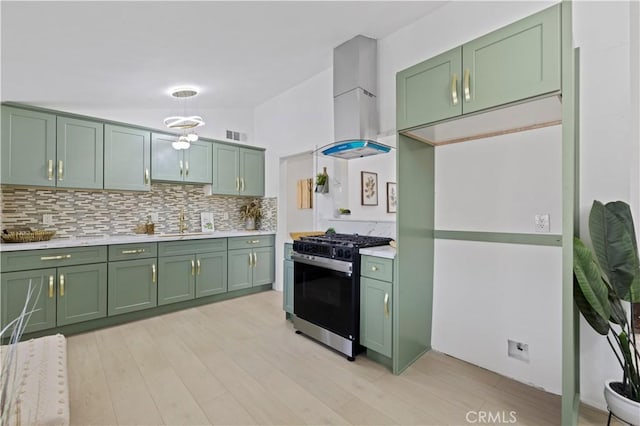 kitchen with wall chimney range hood, stainless steel range with gas stovetop, and green cabinetry